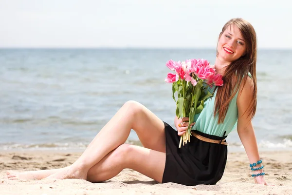 Unga vackra kvinnan stående på stranden gäng blomma — Stockfoto