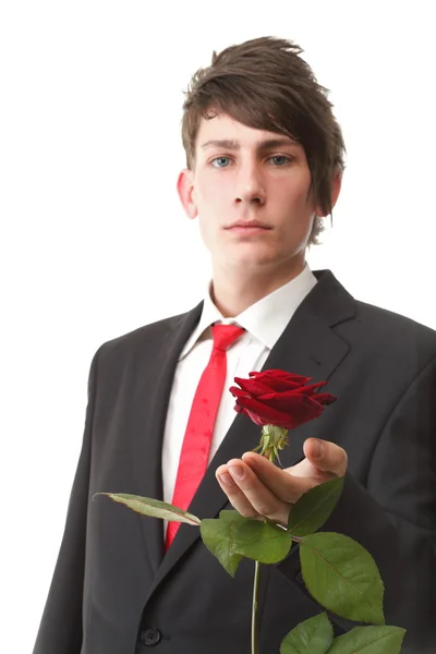 Młody człowiek, prezentując czerwony kwiat róży na białym tle — Zdjęcie stockowe