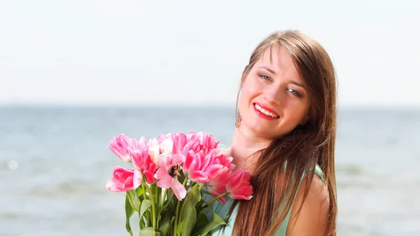 Unga vackra kvinnan stående på stranden gäng blomma — Stockfoto