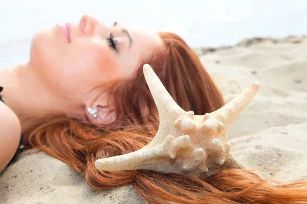 Den vackra flickan ligger på havets kust med skal natur semester — Stockfoto