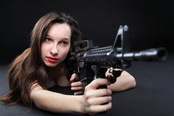 Niña sosteniendo rifle sobre fondo negro —  Fotos de Stock