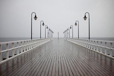 old pier in rain on Baltic sea Orlowo Gdynia Poland clipart