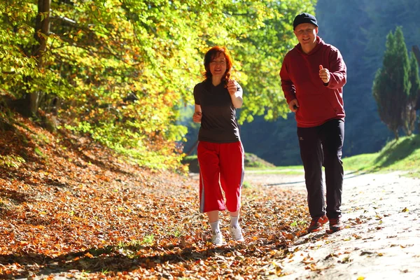 Kvinna och man terränglöpning vandringsled i höst skog — Stockfoto