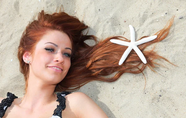 Güzel bir kız deniz kıyısında kabukları doğa tatili ile yatıyor. — Stok fotoğraf