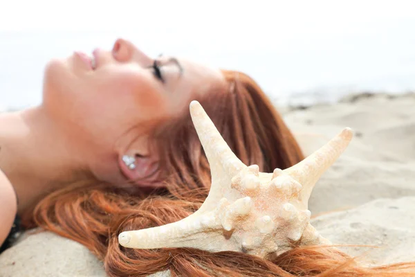 Het mooie meisje ligt op een Zeekust met schelpen natuur vakantie — Stockfoto