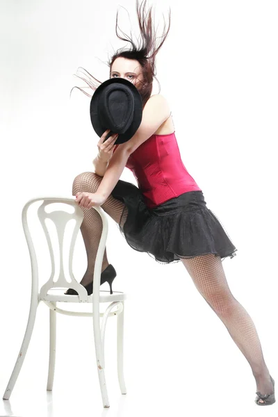 Showgirl woman dance in red corset chair white isolated — Stock Photo, Image