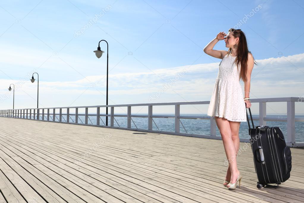 Beautiful woman girl sea mooring suitcase on a pier