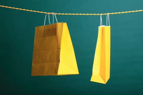 Nákupní žluté dárkové tašky na zeleném pozadí — Stock fotografie
