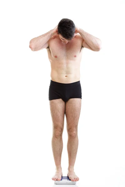 Здоровый молодой человек, стоящий на весах изолированный — стоковое фото