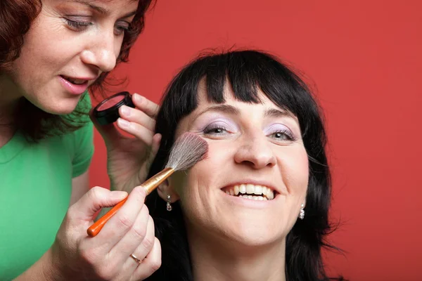 woman paints face with makeup