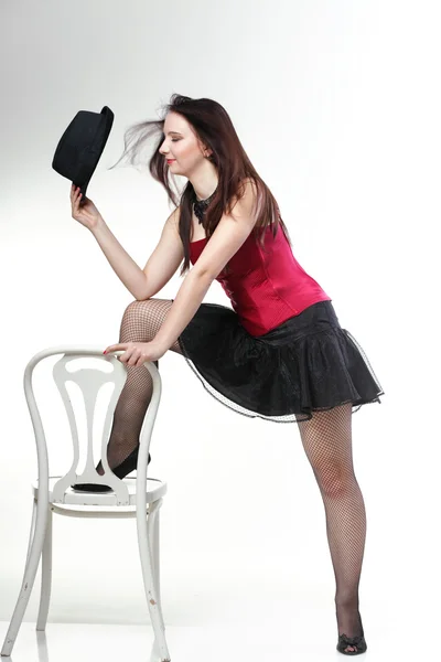 Showgirl woman dance in red corset chair white isolated — Stock Photo, Image