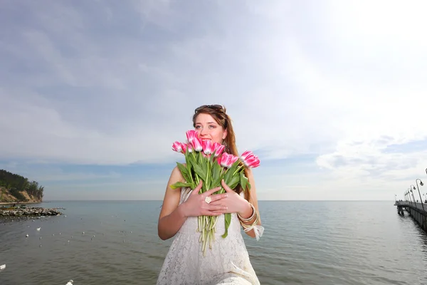 Улыбающаяся женщина с кучей цветов море — стоковое фото
