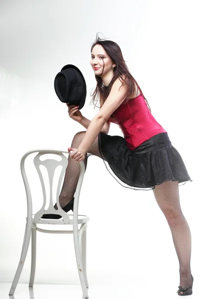 Showgirl woman dance in red corset chair white isolated — Stock Photo, Image