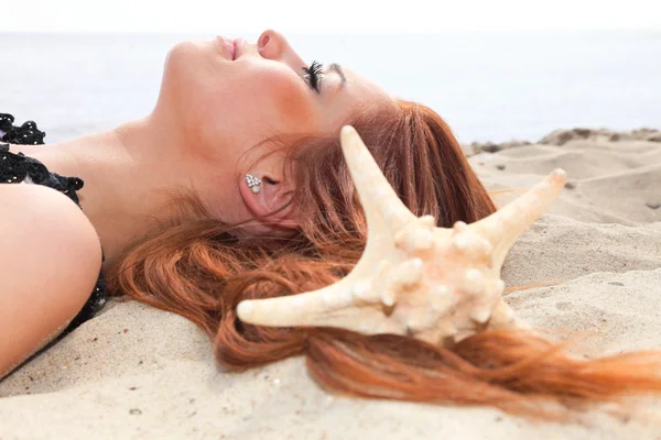 A menina bonita encontra-se na costa do mar com conchas natureza férias — Fotografia de Stock