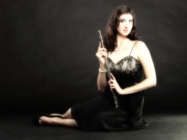 Menina e flauta em um fundo preto — Fotografia de Stock