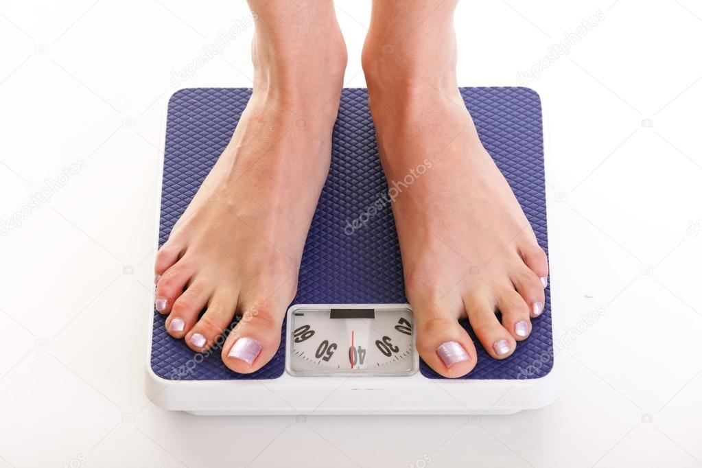 Woman feet and weight scale isolated on white background