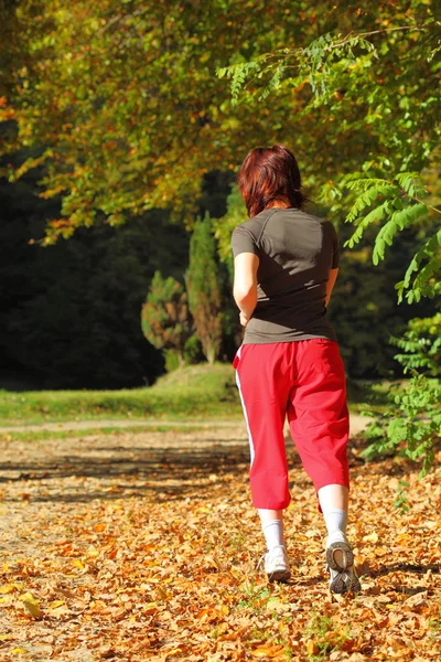 Frau läuft Langlaufloipe im Herbstwald — Stockfoto