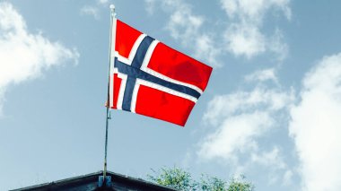 Mavi gökyüzünde dalgalanan Norveç bayrağı