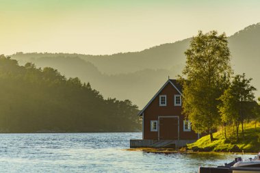 Su fiyortu kıyısındaki ahşap kulübe. Norveç 'te yaz manzarası, İskandinavya