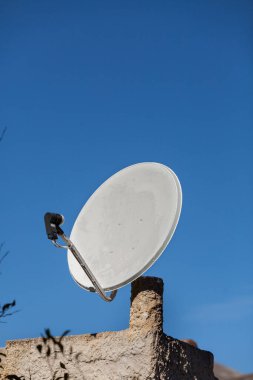 Beyaz uydu çanağı mavi gökyüzü arka plan ile. TV anteni ev çatıda. Kablosuz teknoloji dijital ekipman kavramı.