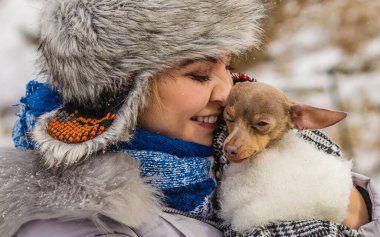 Genç bir kadın soğuk kış gününde en iyi arkadaşını sıcak battaniye eşarbına sardı. Hayvan koruma programı. Evlat edinme kavramı