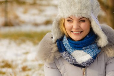 Kış boyunca sıcak aksesuarlar takan güzel bir genç kadın. Açık kürk ve mavi eşarptan yapılmış gri, sıcak şapkalı bir kadın..