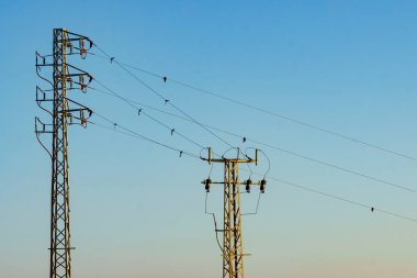 Elektrik iletim direkleri, elektrik hatları mavi gökyüzüne karşı yüksek voltaj kuleleri.