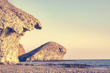 Cabo de Gata Nijar Doğal Parkı 'nda Monsul sahilinde yürüyen bir kadın. Almerya kıyıları. Turist çekmek için büyük lav oluşumu.