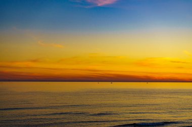 Deniz yüzeyinde gün batımında renkli gökyüzü.