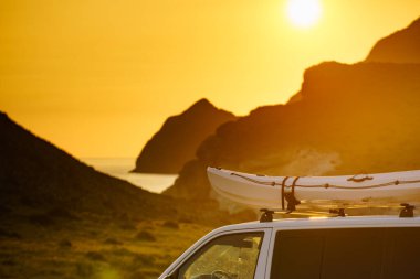 Gün batımında çatıda kanosu olan bir araba, dağ doğasına karşı. Cabo de Gata Nijar Doğal Parkı, Almerya ili, Endülüs İspanya. Etkin yaşam biçimi.