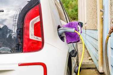 Şarj istasyonunda elektrik prizi olan elektrikli bir araba. Ekolojik ulaşım. Otomotiv teknolojisi kavramı.