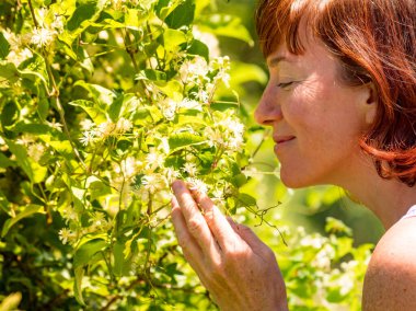 Beyaz çiçek kokan bir kadın. Olgun bir kadın doğanın tadını çıkarıyor.