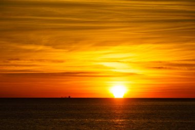 Denizde gün doğumu. Su yüzeyinin altındaki parlak güneş. Güneş ufukta beliriyor. Sabah deniz manzarası.
