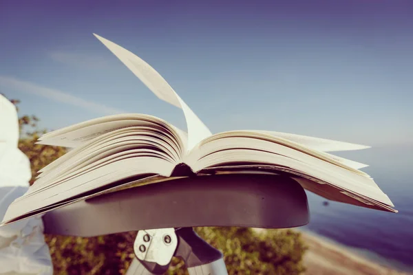 休日の読書 青い海の背景を背景に屋外の椅子に本を開いてください 風になびく本のページ — ストック写真