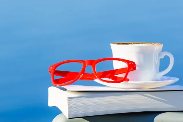 休暇で読書 コーヒーカップ 青い海の水に対する赤い眼鏡 休日の旅行でリラックス 精神衛生上の休憩 — ストック写真