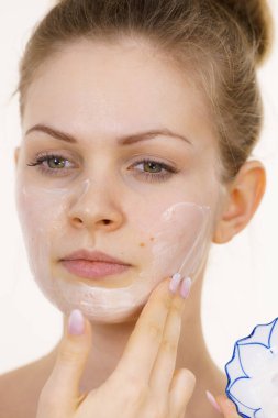 Genç bir kadın krem kozmetik uyguluyor, yüzüne nemlendirici maske takıyor. Güzellik tedavisi. Cilt bakımı.