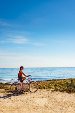 Sahilde bisiklet süren bir kadın. Tatiller, spor ve eğlence..