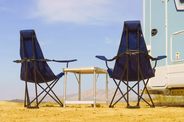 Camp equipment chairs and table at caravan. Wild camping on nature. Holidays and traveling in motor home.