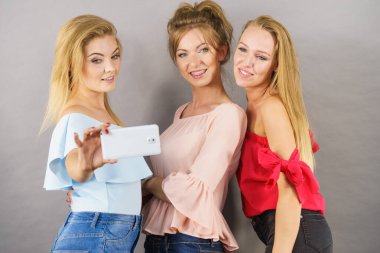 Moda kadınları, akıllı telefon kullanarak kendi resimlerini çekiyorlar. Arkadaşlık zamanlarının tadını çıkarıyorlar..