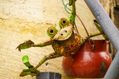 Köy çitlerinde asılı eski kırmızı tencere ve kurbağa. Bahçede dekorasyon