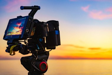 Profesyonel kamera tripodun üzerinde gün batımının görüntülerini çekiyor..