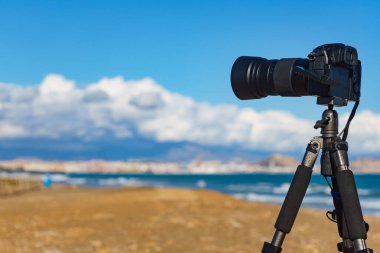 Profesyonel kamera tripodun üzerinde deniz kıyısı manzarasının videosunu çekiyor, İspanya.