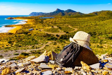Şapka ve sırt çantası, Akdeniz kıyısında yaz yürüyüşü ekipmanları. Murcia bölgesi, Calblanque Bölgesel Parkı, İspanya. Yürüyüş, kamp, aktif yaşam tarzı.