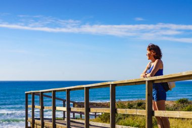 Sahilde dinlenen, gün ışığının tadını çıkaran turist bir kadın. Calblanque Bölgesel Parkı 'nda Cala Magre, Murcia bölgesi İspanya.