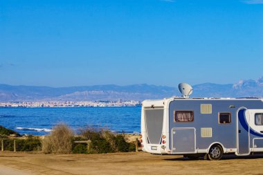 İspanyol sahilinde çatıda çanak antenli bir karavan. Televizyon bağlantısı. Gezici evde tatil..