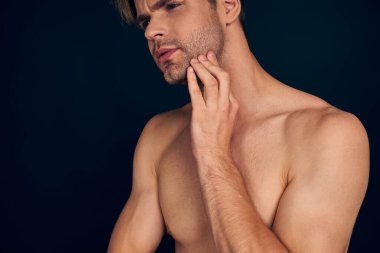 Yakışıklı bir adam. Büyüleyici genç adam, elini çenesinde tutuyor ve gülümsüyor koyu mavi arka planda dururken.