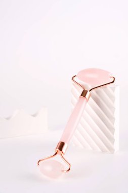 Beyaz arka planda doğal kuvars taşından yapılmış pembe yüzlü masaj aleti. Evde kaldırma ve tonlama tedavisi.