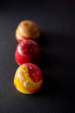 Üst üste yerleştirilmiş farklı renklerde çikolatalı şekerlemelerle modern el resmi. Ürün reklamcılığı konsepti 