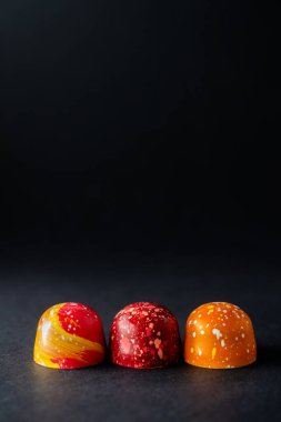 Üst üste yerleştirilmiş farklı renklerde çikolatalı şekerlemelerle modern el resmi. Ürün reklamcılığı konsepti 