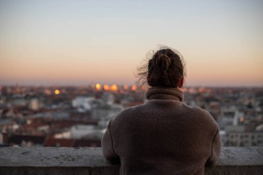 Kuledeki genç kadın şehre bakıyor.